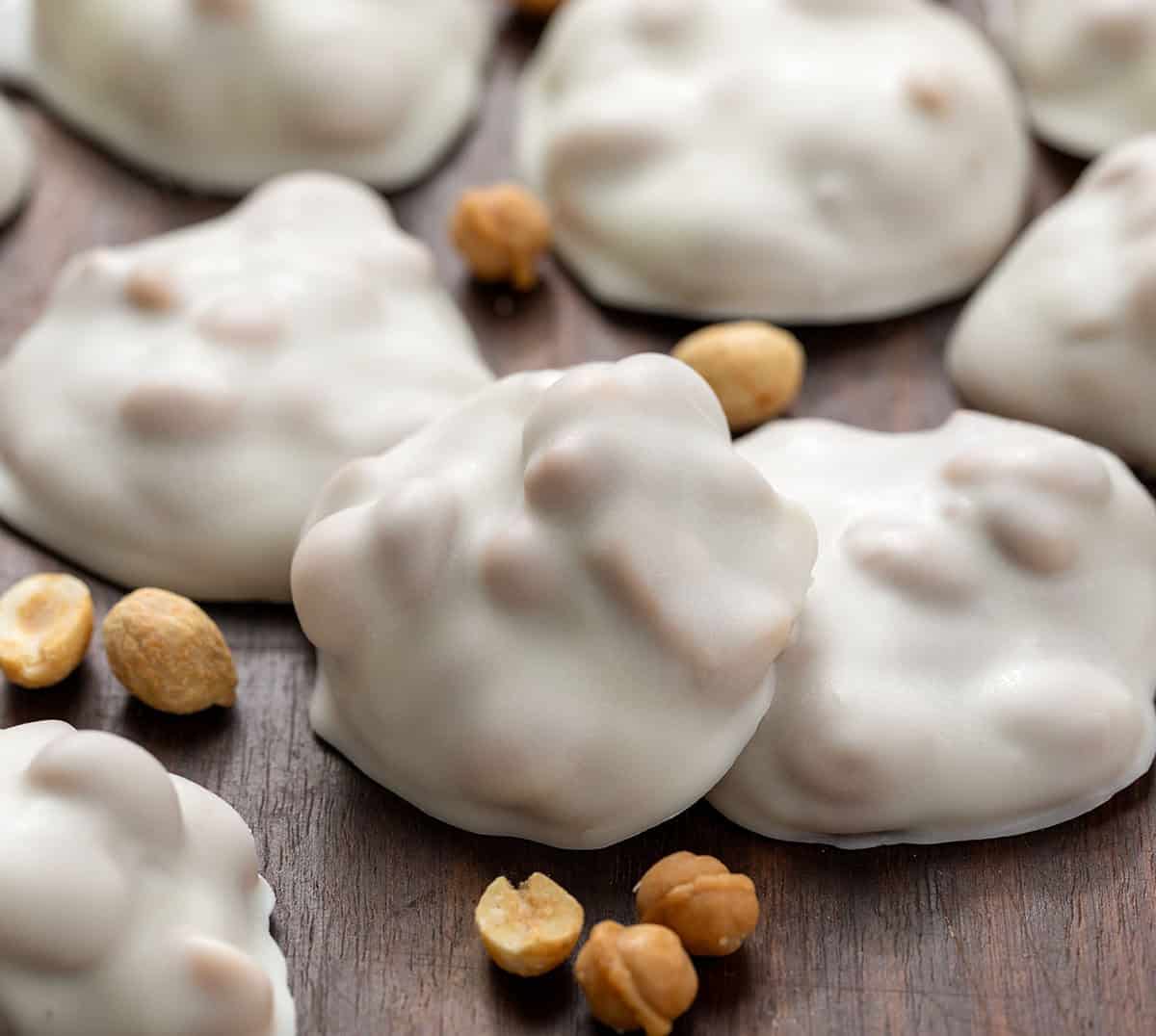 If you love sweet and salty treats, Polar Bear Paws are the perfect candy to make this holiday season. These bite-sized clusters combine crunchy roasted peanuts, gooey caramel, and smooth vanilla almond bark for a candy thatโs irresistible to snack on! Close up of Polar Bear Paws on a wooden table with caramel bits and peanuts.