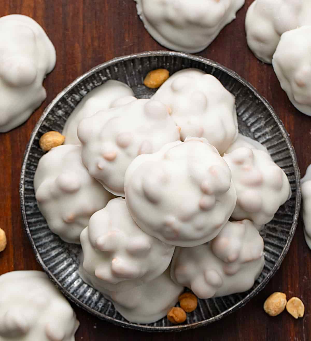 If you love sweet and salty treats, Polar Bear Paws are the perfect candy to make this holiday season. These bite-sized clusters combine crunchy roasted peanuts, gooey caramel, and smooth vanilla almond bark for a candy thatโs irresistible to snack on! Mini tray of Polar Bear Paws on a wooden table from overhead.