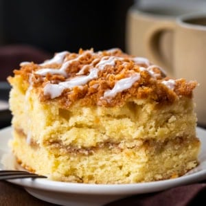 Piece of Snickerdoodle Coffee Cake on a white plate with a bite removed showing the tender crumb and cinnamon swirl.
