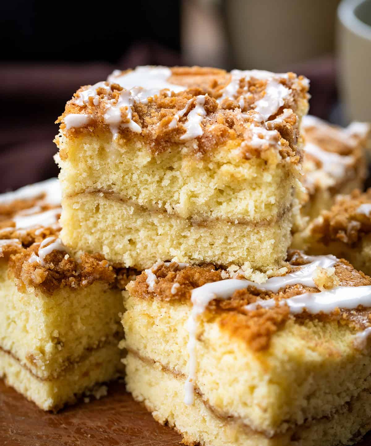If you love snickerdoodles, wait until you try them in coffee cake form! This Snickerdoodle Coffee Cake combines the buttery cinnamon-sugar goodness of the classic cookie with a soft, tender cinnamon coffee cake! Snickerdoodle Coffee Cake stacked on a wooden plate close up.