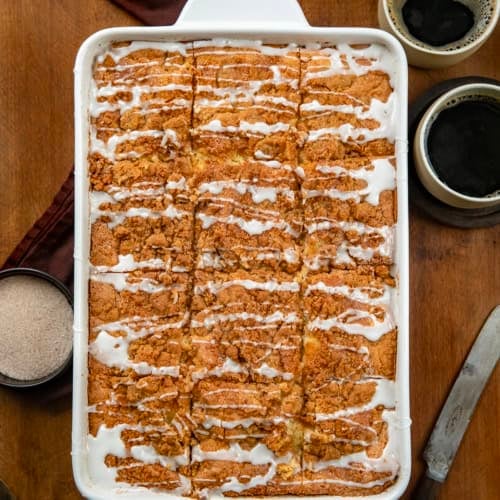 Pan of Snickerdoodle Coffee Cake on a wooden table from overhead with coffee cups.