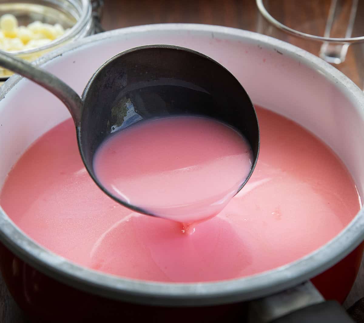 Using a ladle in to pour Strawberry Hot Chocolate into a pot.