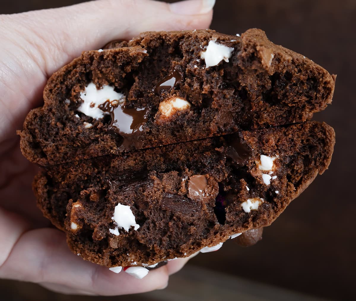 Hand holding a Triple Chocolate Peppermint Cookie showing the tender inside with melty chocolate.
