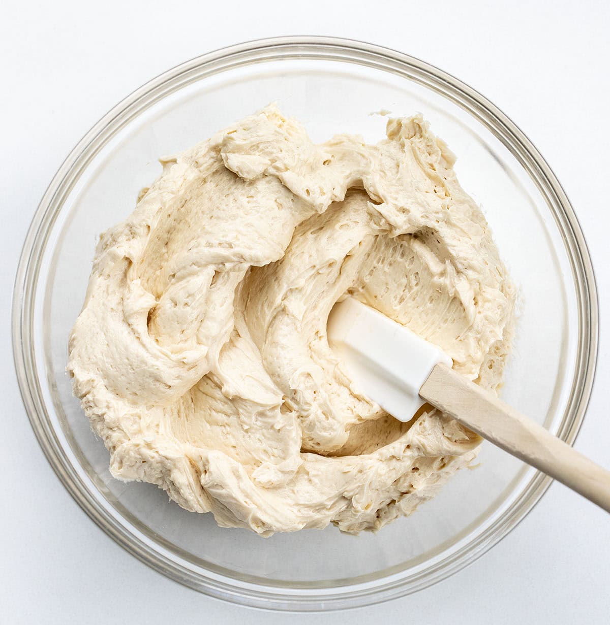 Glass bowl of Brown Sugar Ermine Frosting with a spatula in it.
