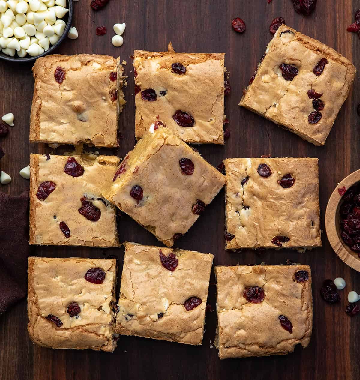 Cranberry White Chocolate Blondies cut into squares on a wooden table from overhead.