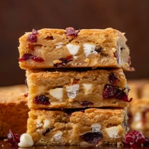 Stack of Cranberry White Chocolate Blondies on a wooden table close up.