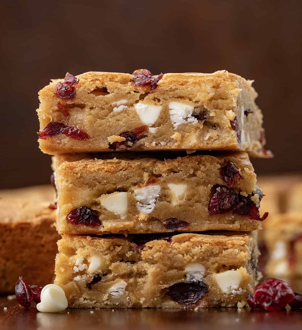 Stack of Cranberry White Chocolate Blondies on a wooden table close up.