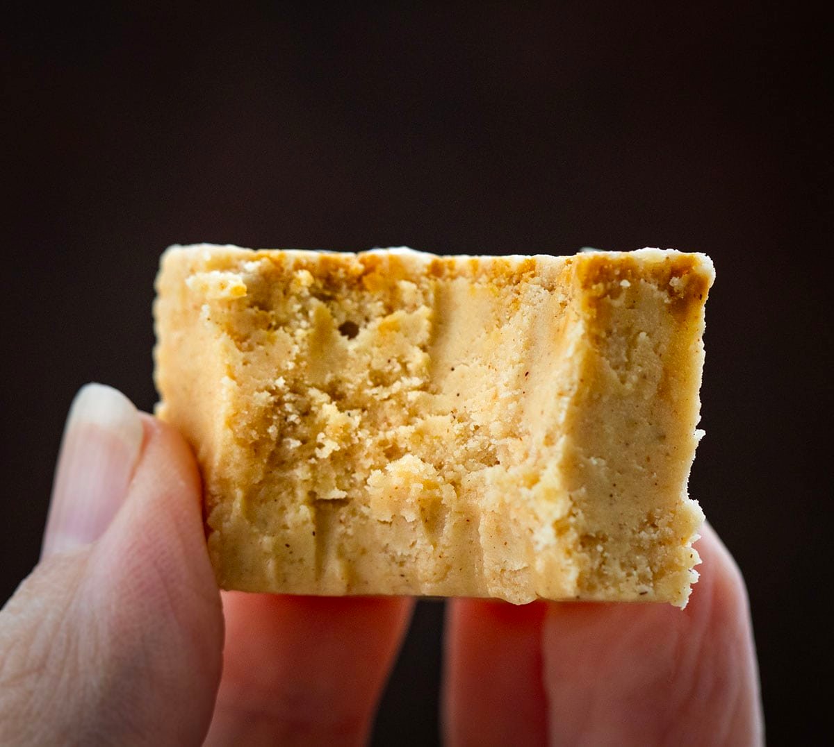 Hand holding a piece of Gingerbread Fudge that has a bite taken out of it.