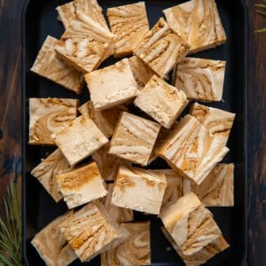Tray of Gingerbread Fudge cut into small pieces on a wooden table from overhead.