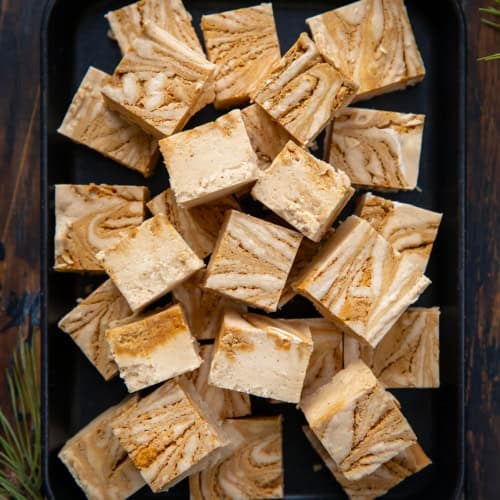 Tray of Gingerbread Fudge cut into small pieces on a wooden table from overhead.