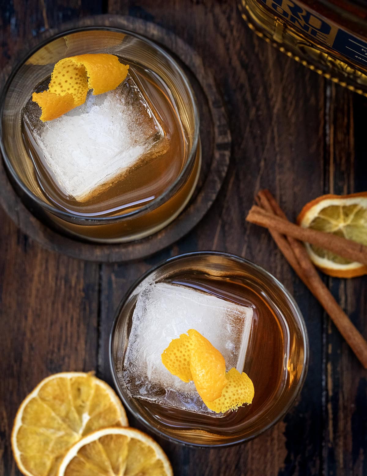 Warm, cozy, and perfectly spiced for fall, this Maple Old Fashioned is a classic cocktail with a seasonal twist! Whether you’re winding down after a busy day or serving a cocktail at a cool-weather gathering, this drink is easy to make and sure to impress! Glasses of Maple Old Fashioned on a wooden table from overhead.