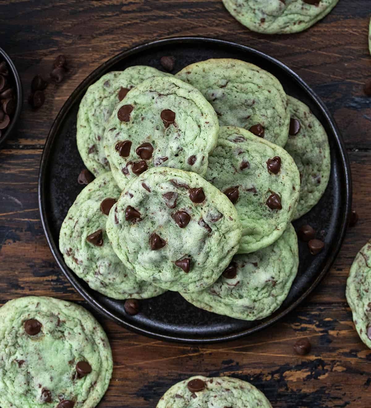 Black plate with Mint Chocolate Chip Cookies on it on a wooden table from overhead.