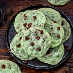 Black plate with Mint Chocolate Chip Cookies on it on a wooden table from overhead.