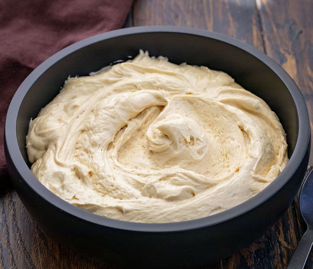 Rich, creamy, and perfectly spiced, this Molasses Cream Cheese Frosting adds cozy holiday flavor to any dessert. The tangy cream cheese pairs beautifully with the deep sweetness of molasses for a frosting that tastes like gingerbread in creamy form! Black bowl filled with Molasses Cream Cheese Frosting.