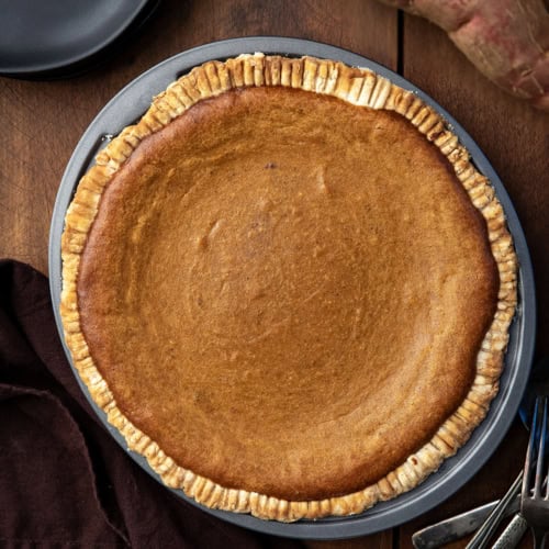 Whole Roasted Sweet Potato Pie on a wooden table from overhead.
