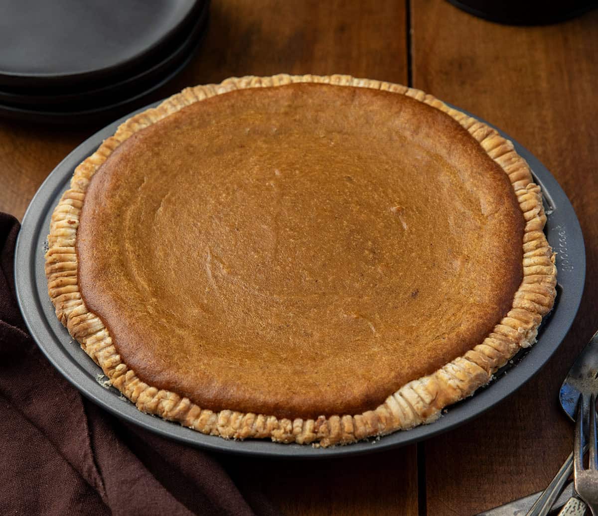 Rich, creamy, and perfectly spiced, this Roasted Sweet Potato Pie elevates the classic holiday dessert with roasted fresh sweet potatoes for deeper flavor! Whole Roasted Sweet Potato Pie on a wooden table.