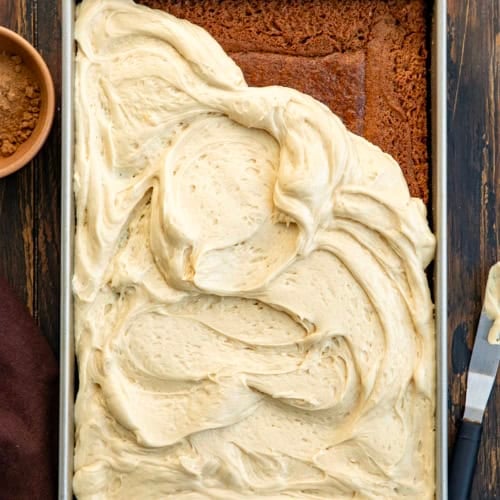 Sour Cream Spice Cake that is partially frosted on a wooden table.