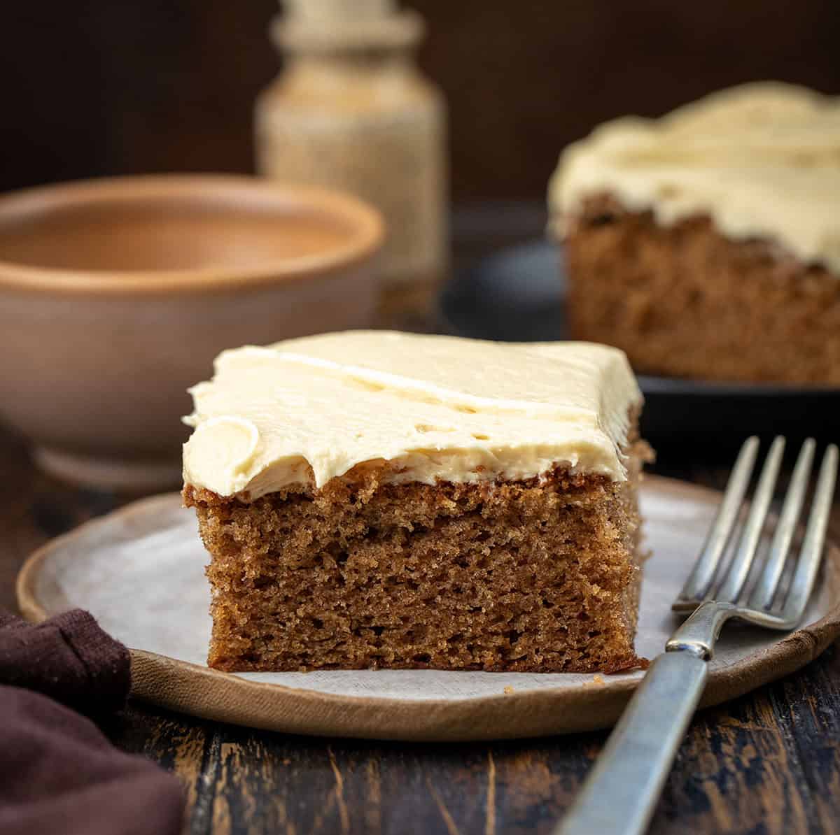 Plates with pieces of Sour Cream Spice Cake on them on a wooden table.