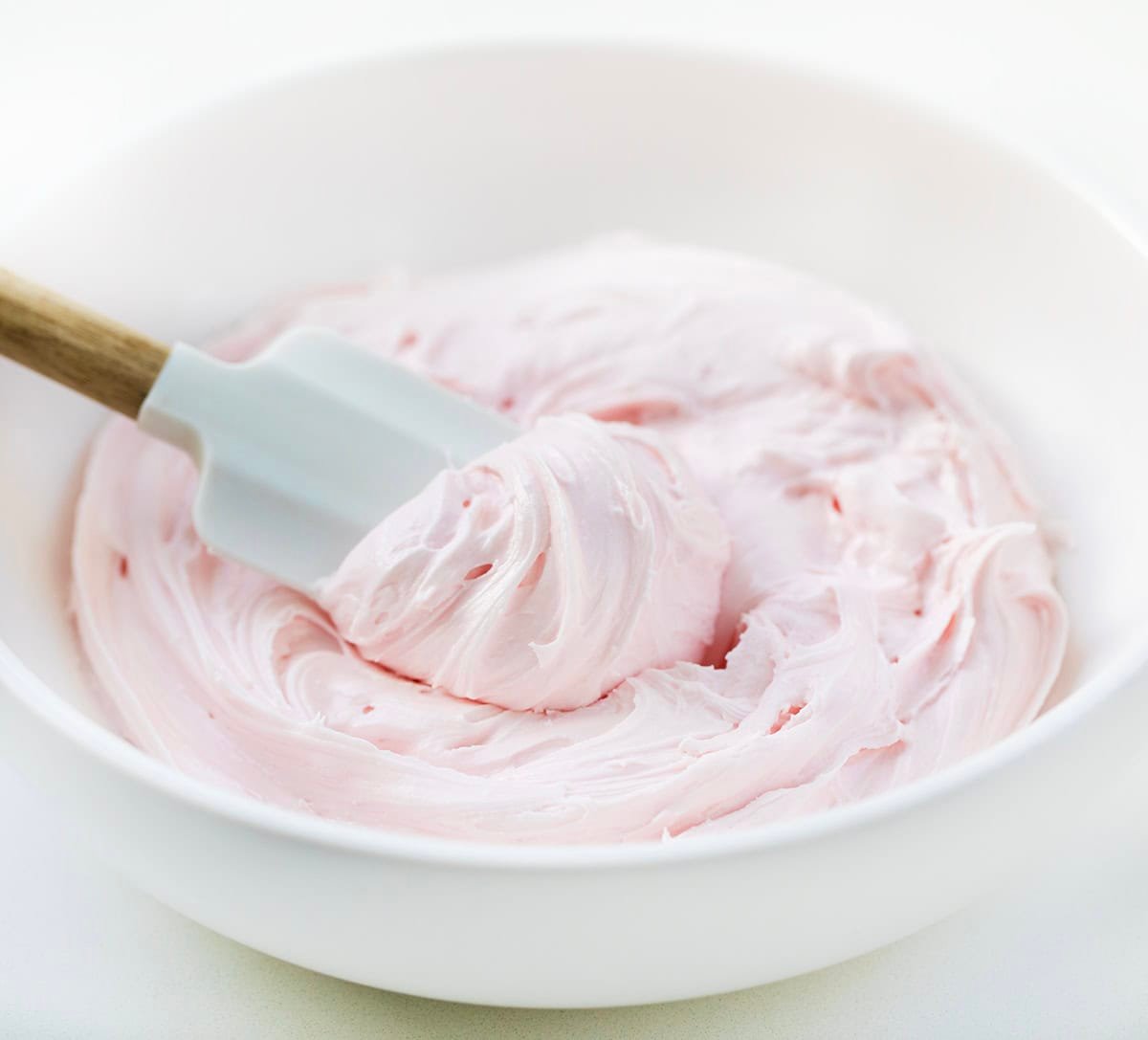 If you love all things pink, fluffy, and berry-sweet, this Strawberry Marshmallow Frosting is about to be your new favorite! It’s ultra-light, perfectly creamy, and gets its strawberry flavor from extract and strawberry marshmallow fluff with no cooking, just pure whipping magic. White bowl of Strawberry Marshmallow Frosting with a spatula in it.