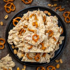 Black plate of White Chocolate Peanut Butter Pretzel Bark on a table from overhead.