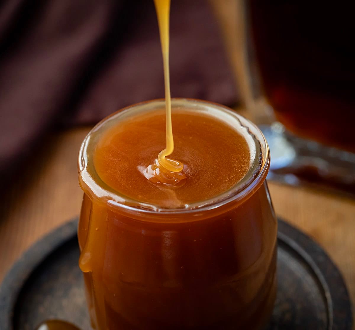 Rich, buttery, and boozy in the best way, this Bourbon Caramel Sauce takes classic caramel to the next level. Itโs sweet, slightly smoky, and full of deep, warm flavor thanks to a splash of bourbon! Drizzling Bourbon Caramel Sauce into a small glass jar.
