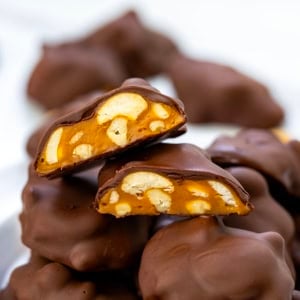 Stack of Chocolate Caramel Cashew Clusters with top one cut in half.