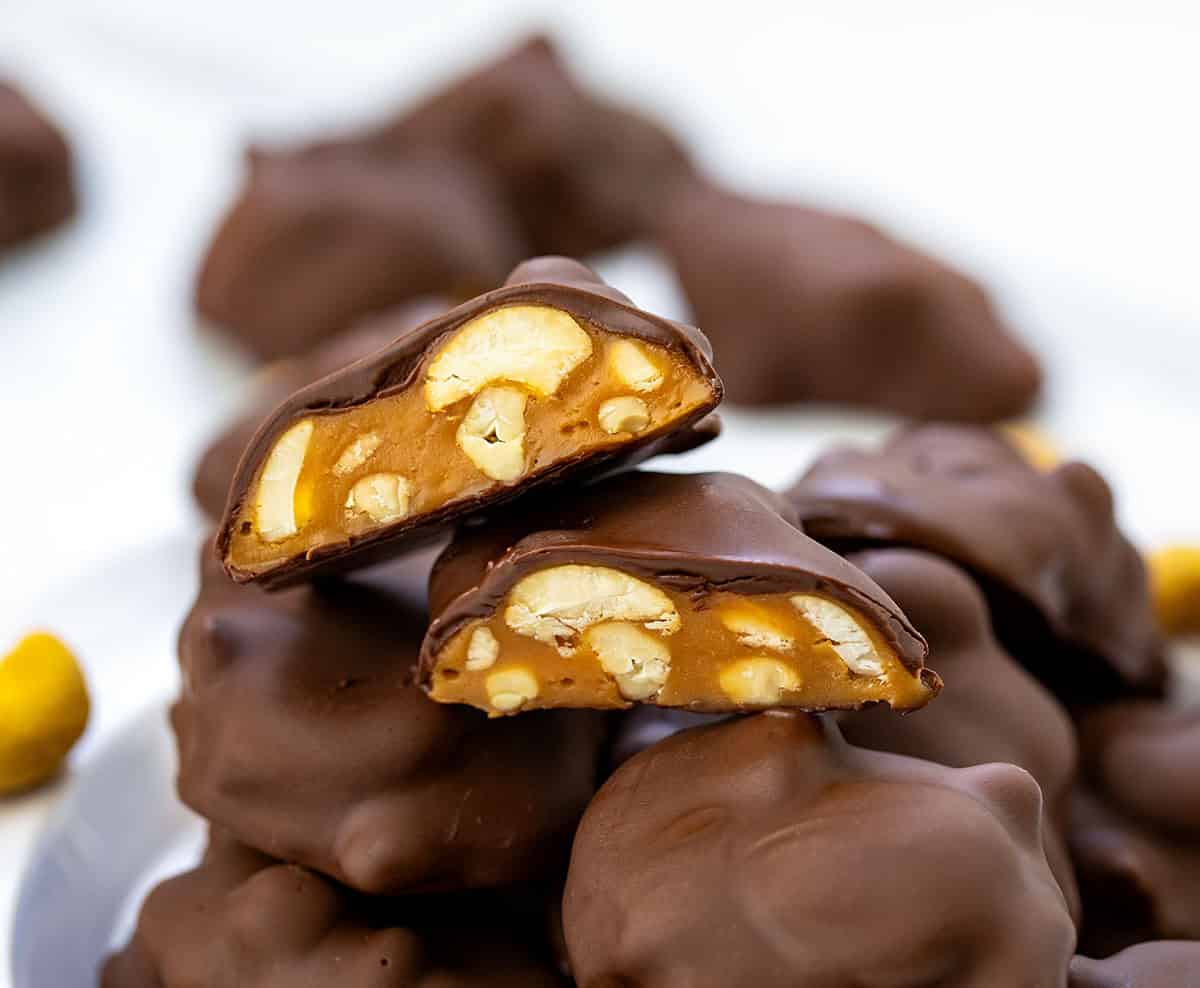 Stack of Chocolate Caramel Cashew Clusters with top one cut in half.