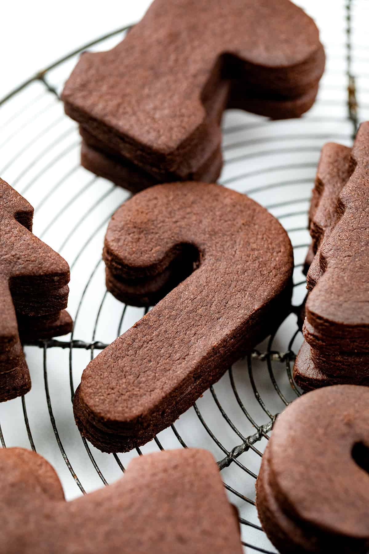 Cut-Out Chocolate Sugar Cookies are soft-centered, rich in cocoa, and hold their shape perfectly for decorating! Chocolate Sugar Cookies on a cooling rack stacked.
