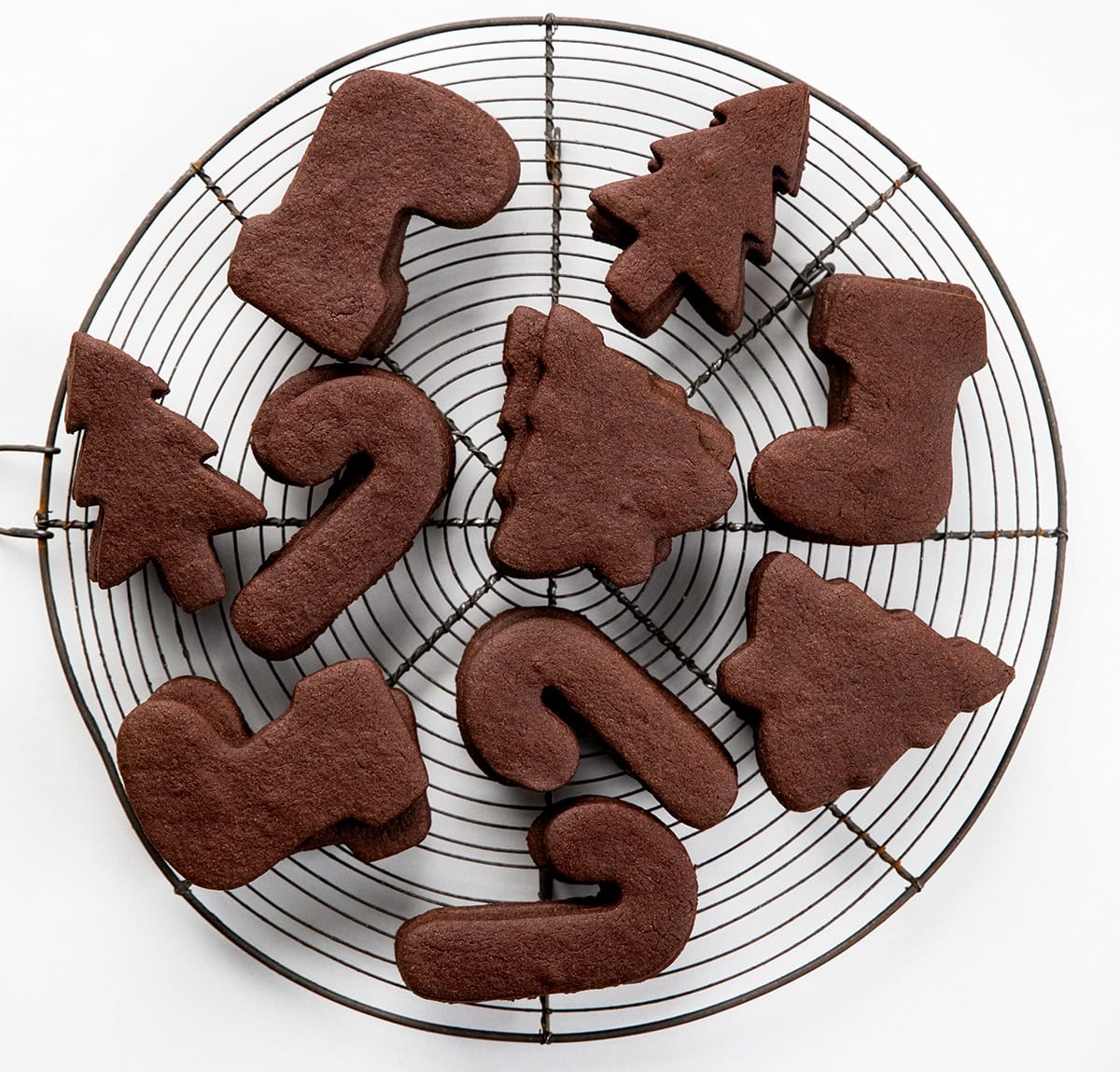 Cut-Out Chocolate Sugar Cookies are soft-centered, rich in cocoa, and hold their shape perfectly for decorating! Chocolate Sugar Cookies on a round cooling rack on a white table from overhead.