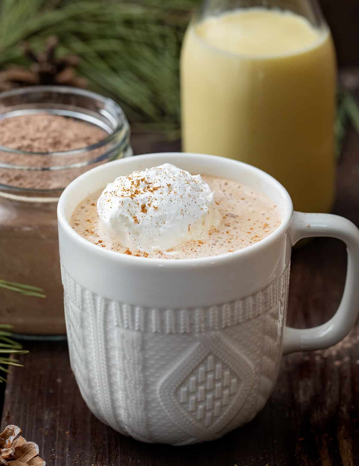 Full mug of hot Eggnog Hot Cocoa Mix next to the mix itself. 