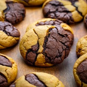 Ginger Brownie Cookies on a wooden table laid out and one cookie is resting on another.