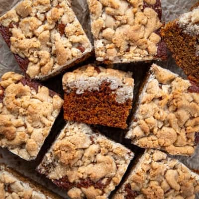 Cut pieces of Gingerbread Coffee Cake on a wooden table with a couple of pieces on their side showing the tender crumb.