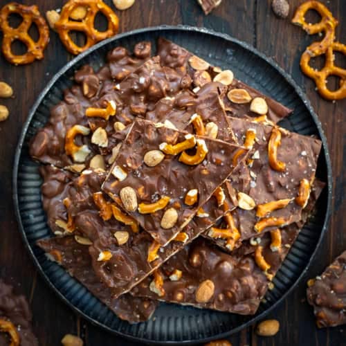 Small platter of pieces of Milk Chocolate Peanut Butter Pretzel Bark on a wooden table from overhead.
