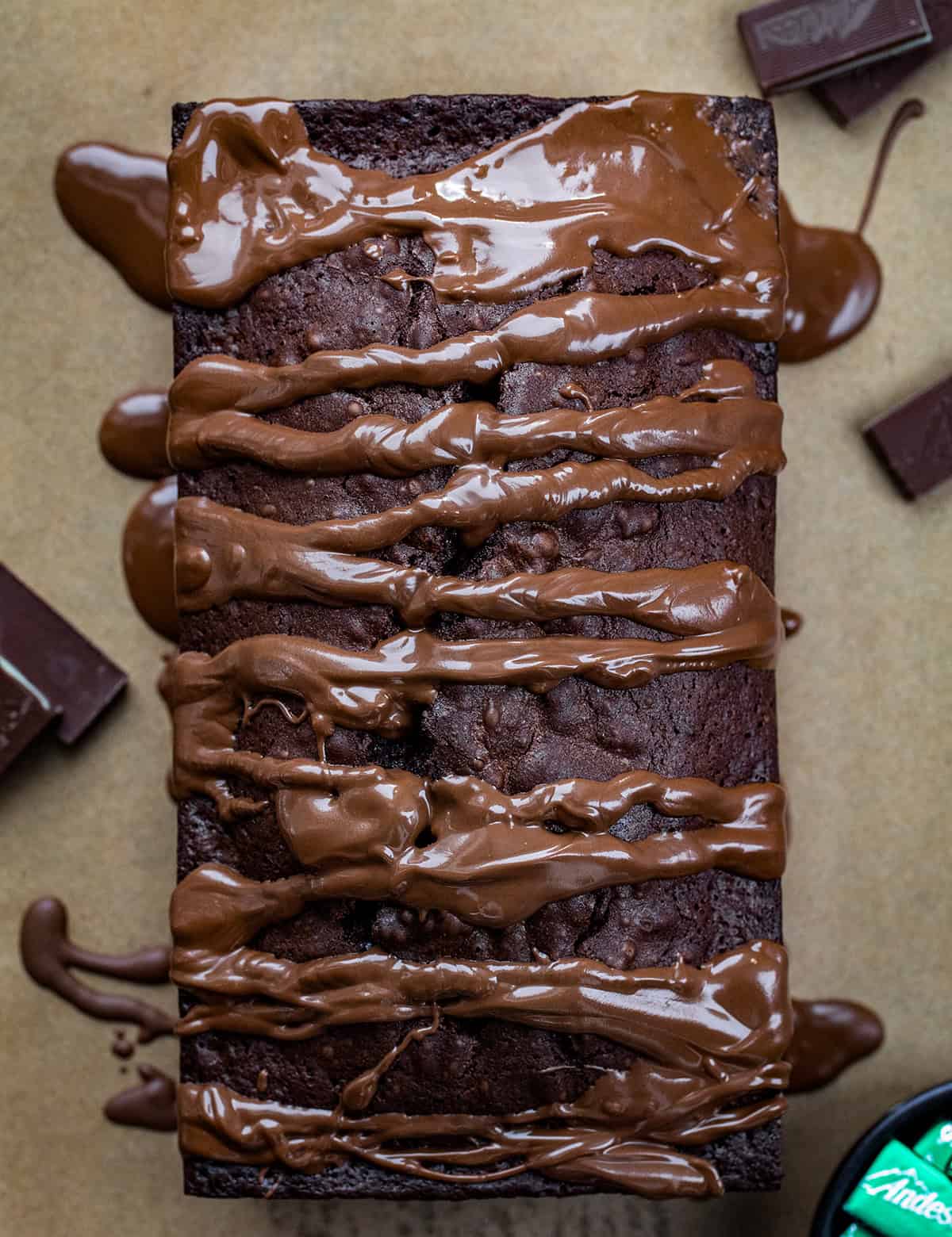 This Peppermint Brownie Bread is a rich and fudgy quick bread that is packed with chocolatey goodness with a refreshing hint of mint. It’s based on my popular brownie bread! Loaf of Peppermint Brownie Bread covered and chocolate glaze from overhead.