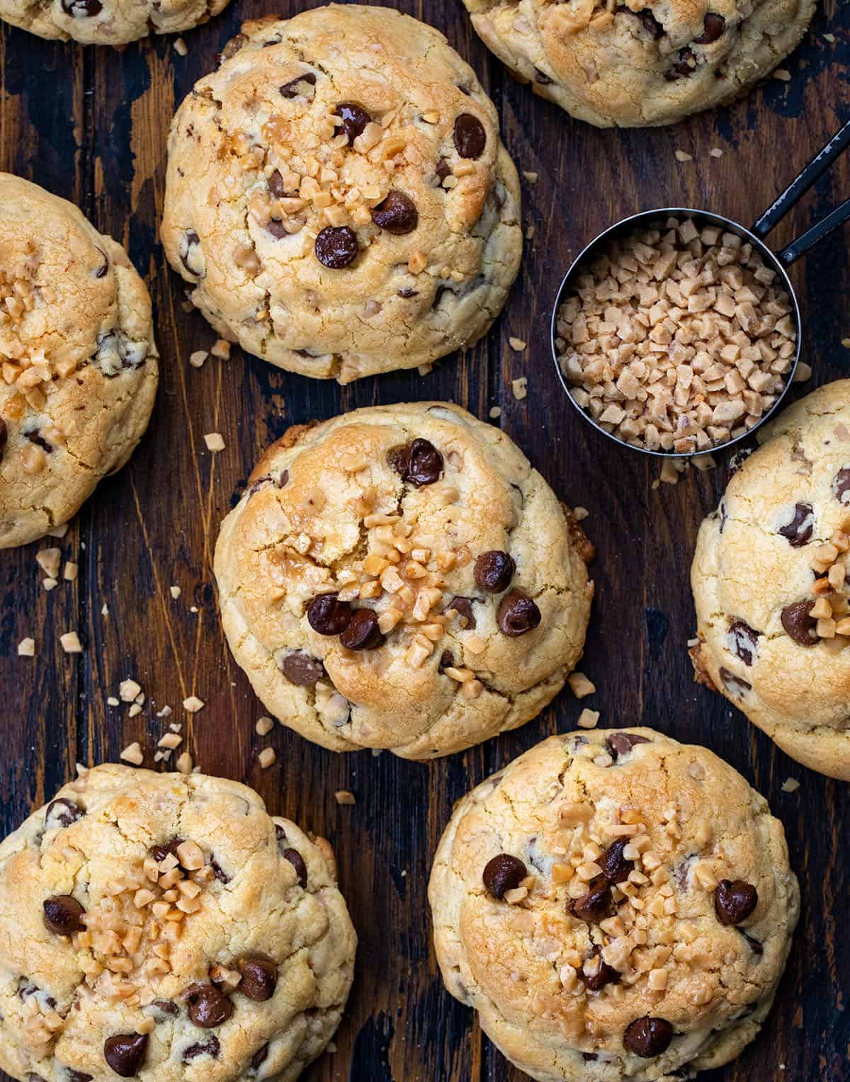 If you love cookies with a soft, chewy center, crispy edges, and a little extra crunch, these Thick and Chewy Chocolate Toffee Cookies are for you. They’re based on my tried-and-true thick and chewy chocolate chip cookies, but with the addition of buttery toffee bits for a sweet, caramelized crunch in every bite! Thick and Chewy Chocolate Toffee Cookies on a wooden table with toffee bits from overhead.