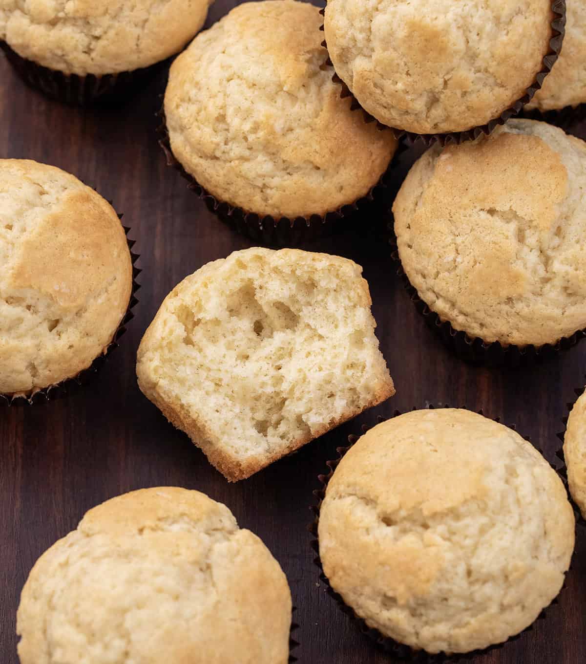 Buttermilk Muffins on a wooden table from overhead with the middle muffin halved showing inside texture.