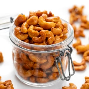 Candied Cashews in a jar with a lid on a white table.