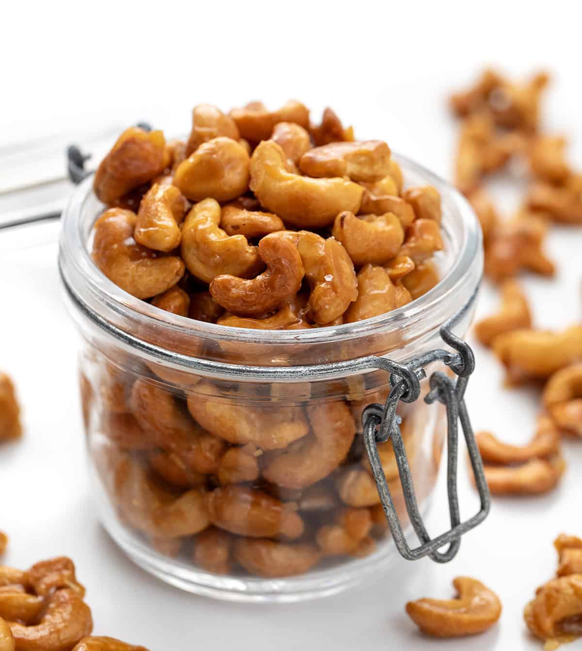 Candied Cashews in a jar with a lid on a white table.