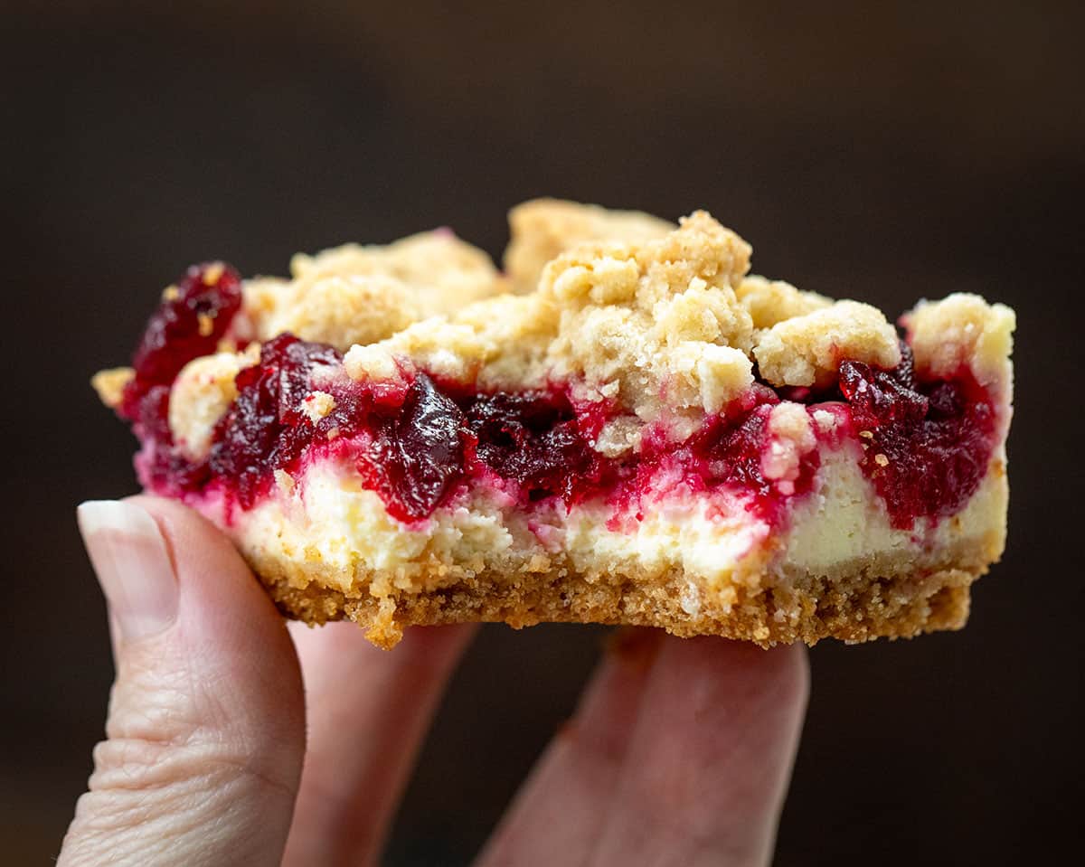 Hand holding a bit into Cranberry Cheesecake Bar.
