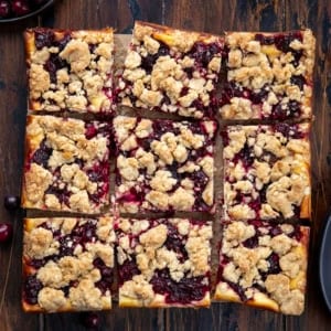 Cranberry Cheesecake Bars cut into squares on a wooden table from overhead.