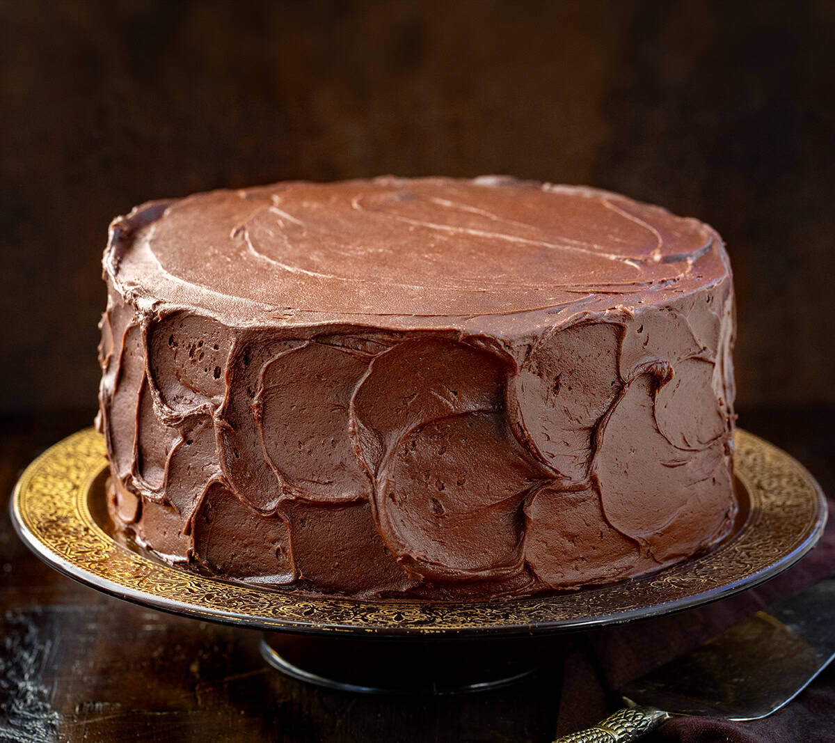 Devil's Food Cake on a glass vintage cake stand on a wooden table.