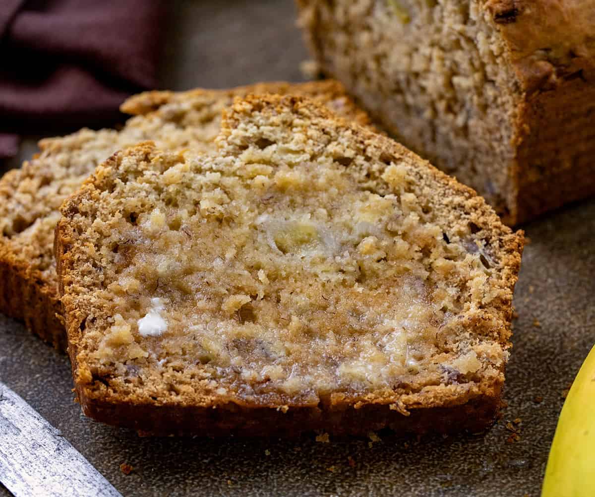 This Honey Banana Bread is a cozy quick bread that’s naturally sweetened with honey instead of sugar. The bananas keep the loaf soft and moist, and the honey gives a warm flavor and golden edges! Close up of melted butter on a slice of Honey Banana Bread.