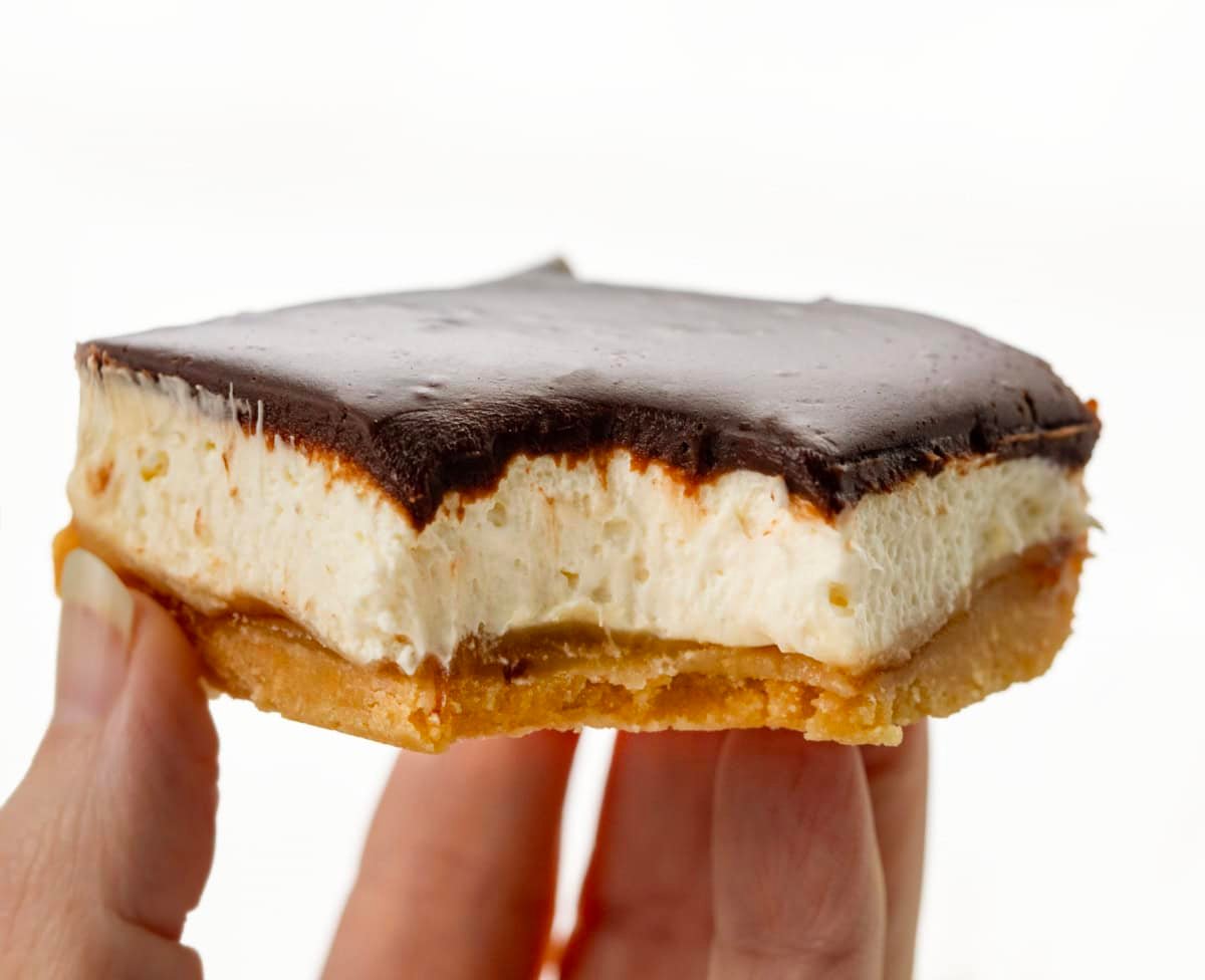 Hand holding a bit into Millionaire's Cheesecake Bar.