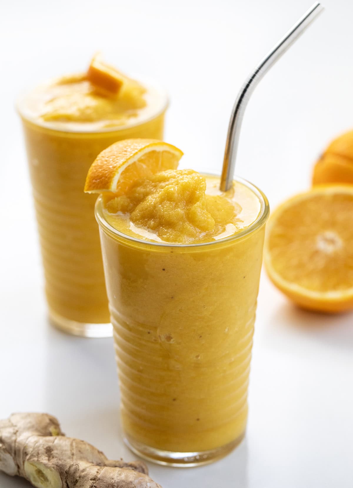 Glasses of Pineapple Ginger Turmeric Smoothie, one with a straw.
