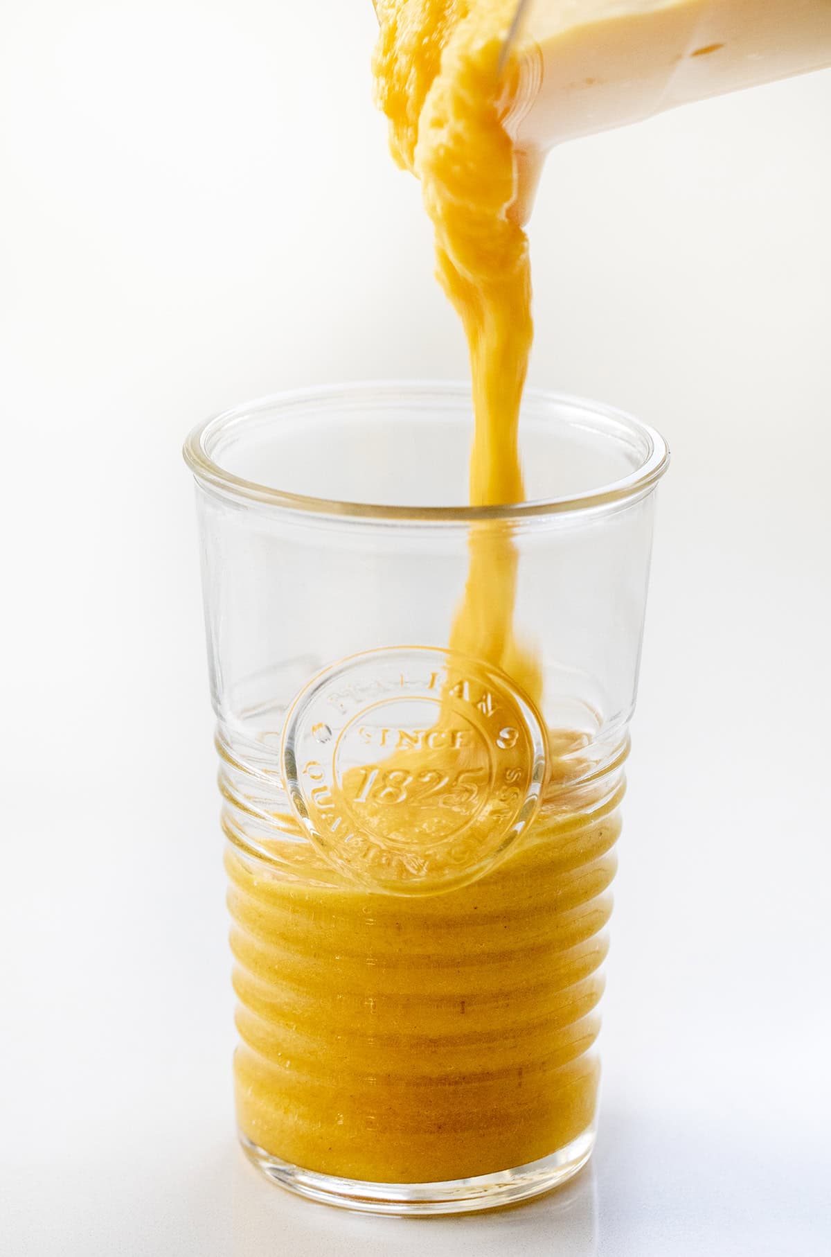 Pouring Pineapple Ginger Turmeric Smoothie into a glass.