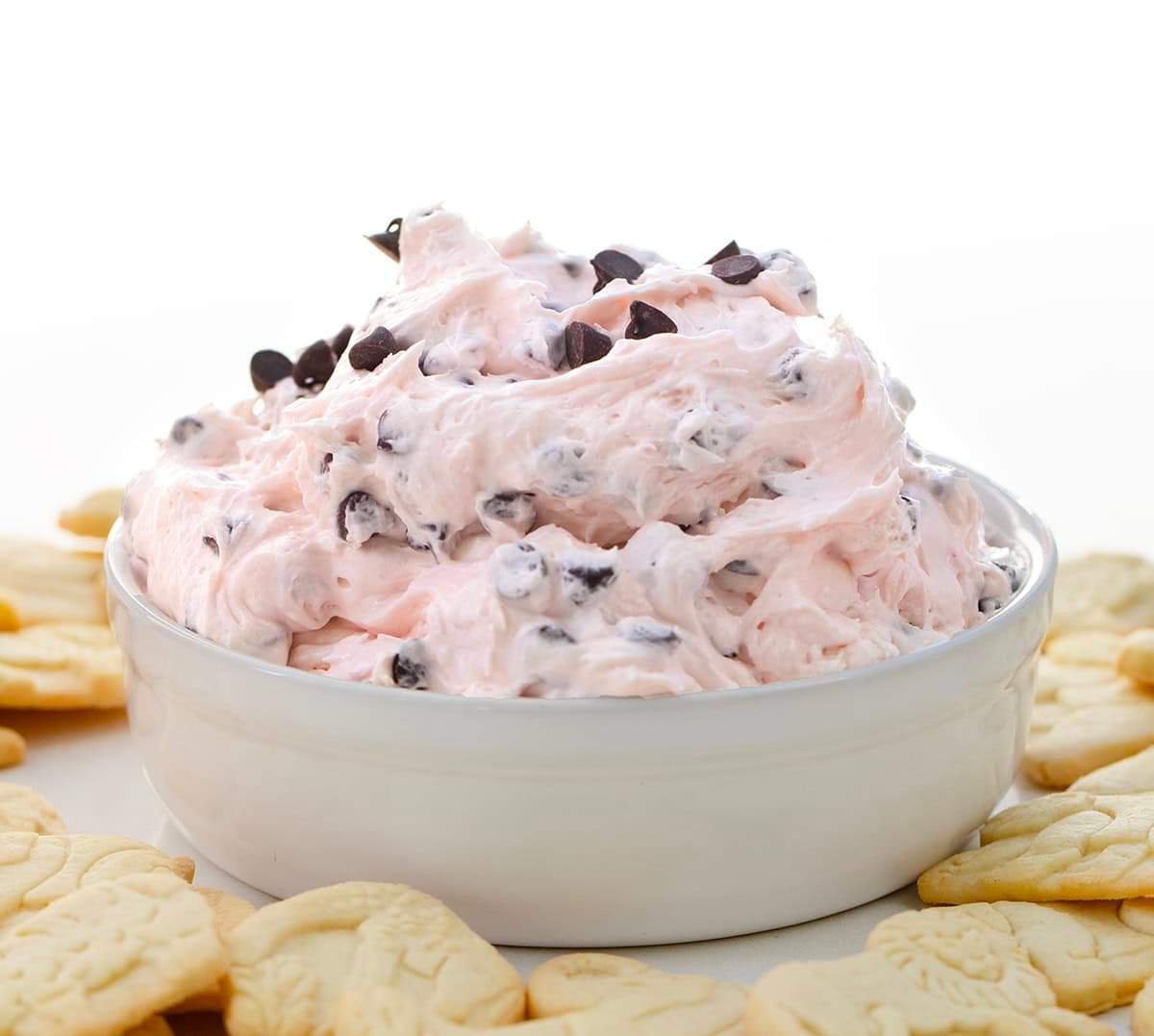 White bowl filled with Valentine's Booty Dip surrounded by animal crackers.