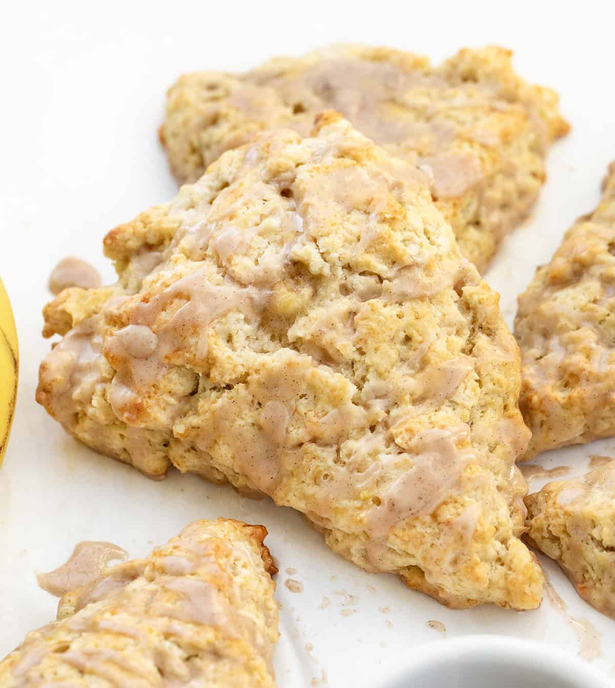 I love these banana scones with maple glaze because they feel like something from a cute bakery case! The edges bake up crisp and golden, and the centers stay soft and tender. The cinnamon maple glaze on top adds sweetness and makes them feel extra special! Close up of Banana Scones with maple glaze.