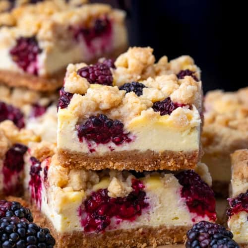 Close up of a small stack of Blackberry Cheesecake Bars surrounded by more bars.