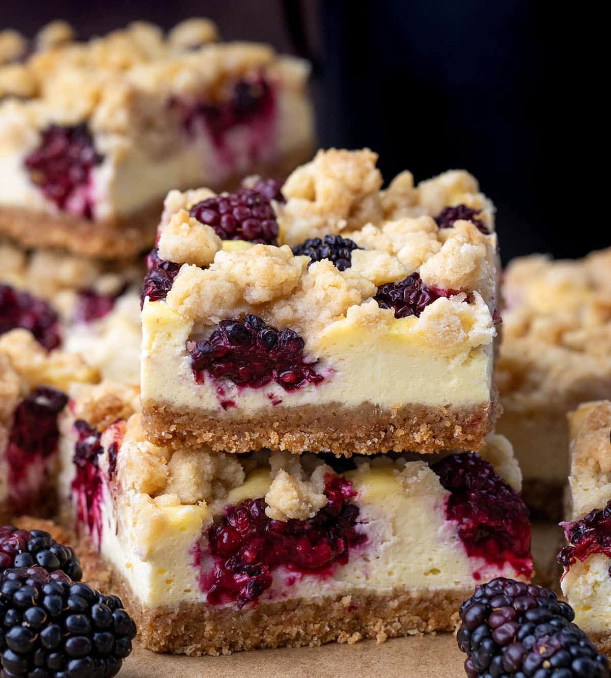Close up of a small stack of Blackberry Cheesecake Bars surrounded by more bars.