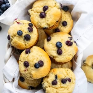 Basket filled with Blueberry Buttermilk Muffins on a white table from overhead.